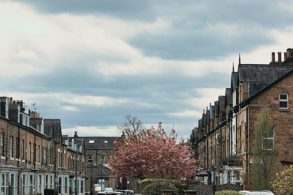 A street of traditional British terraced houses under a soft overcast sky